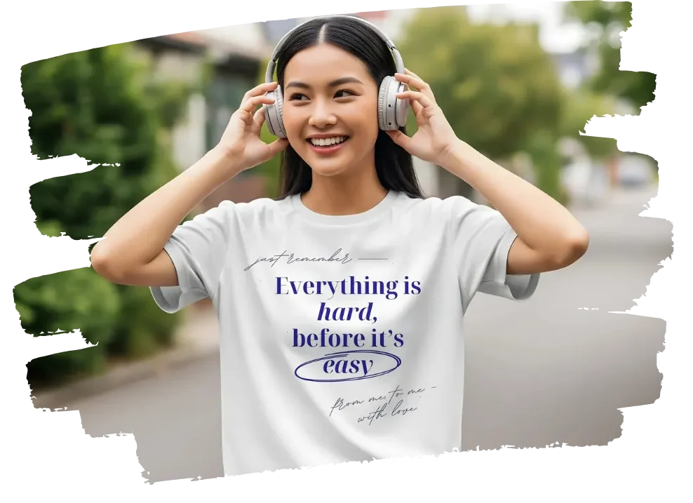 Smiling girl wearing headphones and a motivational quote T-shirt that says "Everything is hard before it’s easy