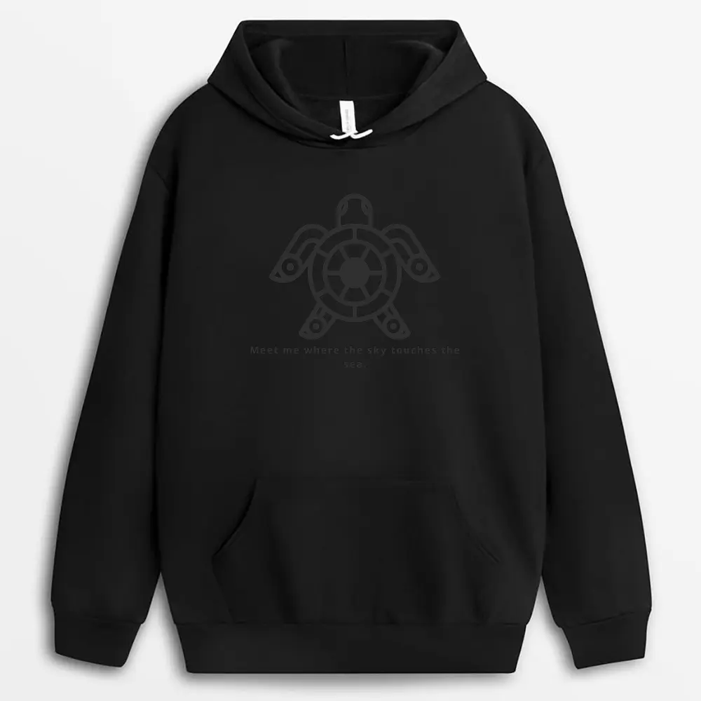 Overhead shot of a hoodie laid flat on sand, featuring subtle horizon prints and a kangaroo pocket, designed to evoke forward-thinking energy and minimalist calm.