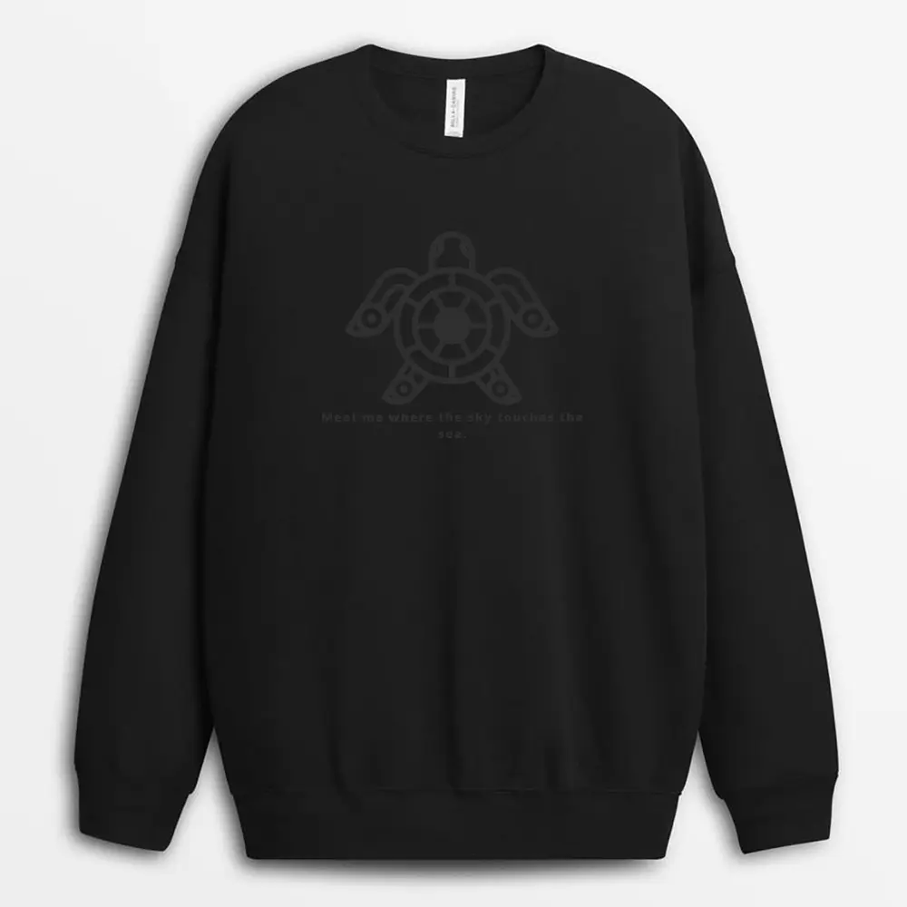 Moody image of a gray sweatshirt photographed near crashing waves, with contour-style ocean prints wrapping around the hem, symbolizing raw nature and survival.